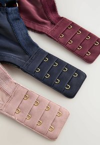 Trzy zapięcia z tyłu biustonoszy w kolorach mauve, granatowym i różowym, z trzema rzędami złotych haczyków na białym tle.