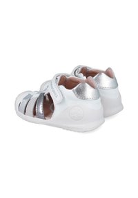 Sandalias blancas con detalles plateados, parte trasera cerrada, punta descubierta, correas ajustables y plantilla texturizada de color claro. Suela de goma con detalle del logo.