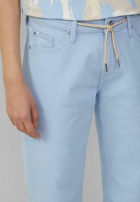 Pantalones de algodón azul claro con cintura elástica y detalles en beige, bolsillos laterales y una textura suave.