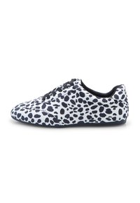 Valkoiset sneakerit, joissa on mustia epäsäännöllisiä laikkuja, mustat nauhat ja matala pohja, kuvattuna sivusta valkoista taustaa vasten.