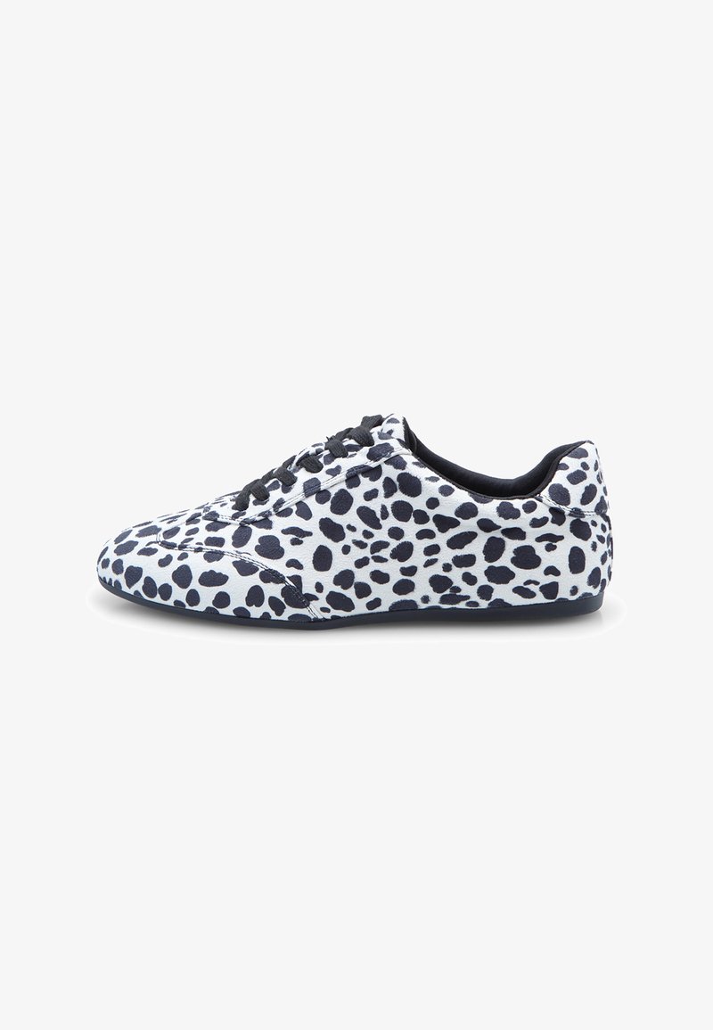 Weißer Sneaker mit schwarzen unregelmäßigen Punkten, schwarzen Schnürsenkeln und flacher Sohle, seitlich auf einem weißen Hintergrund dargestellt.