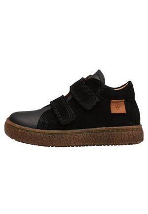 Baskets en suède et cuir noir avec deux bandes Velcro, une semelle en caoutchouc brun texturé et un petit patch logo beige sur le côté.