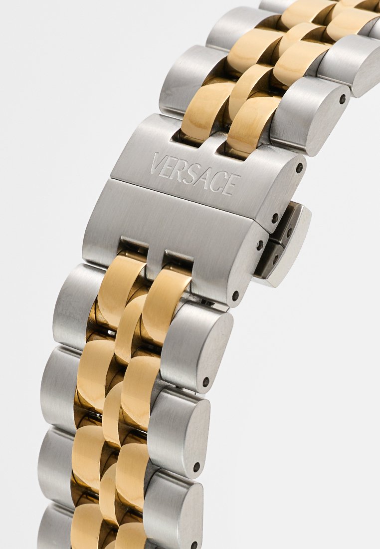 Bracelet de montre en métal avec des segments de maillon alternant en acier inoxydable et doré. Gravé "VERSACE" sur le fermoir, présentant une finition polie.