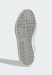 Svijetlosivi potplat tenisica s teksturiranom gumom za bolje prianjanje, s Adidas brandom i valovitim uzorkom, zaobljenim vrhom i bočnim rubovima.