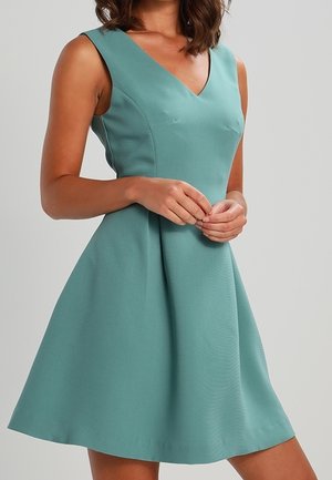 Ein ärmelloses Kleid mit V-Ausschnitt aus einem weichen, strukturierten tealfarbenen Stoff, mit figurbetontem Oberteil und ausgestelltem Rock für eine klassische Silhouette.