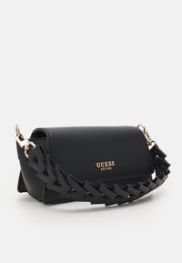 Borsa nera in similpelle liscia, con tracolla intrecciata, dettagli in ottone dorato e logo del marchio sul davanti.