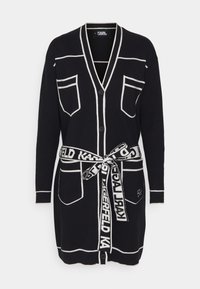 Schwarzer langer Cardigan mit weißen Akzenten, Knopfverschluss, Brust- und Hüfttaschen sowie einem gebundenen Gürtel mit dem Text "Karl Lagerfeld".
