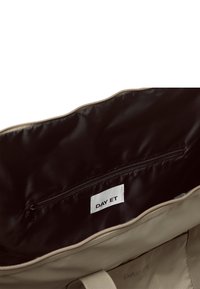 Beiger Tascheninneraum mit schwarzer Innenauskleidung, ausgestattet mit einer Reißverschlusstasche und einem sichtbaren "DAY ET"-Etikett. Einfaches und stilvolles Design.