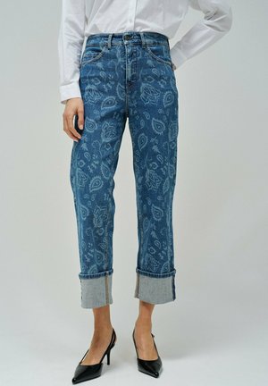 Denim jeans with a paisley pattern in light blue on a dark blue background. Straight-legged, cuffed at the ankles, featuring a classic five-pocket design.