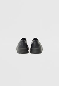 Svarta lädersneakers med en slät yta, rund tå, vadderad sula, minimalistisk design och subtila sömsdetaljer.