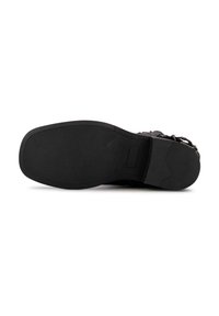 Suela de zapato negra con una superficie de goma texturizada y forma curvada; presenta un inserto rectangular y un diseño minimalista.