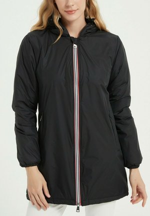 Veste noire matelassée avec capuche, fermeture éclair intégrale avec un accent rayé rouge et blanc, poignets élastiqués et poches latérales.