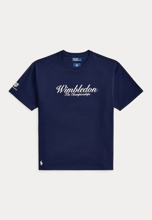 Μπλε σκούρο κοντομάνικο T-shirt με το κείμενο "Wimbledon The Championships" στο μπροστινό μέρος, λογότυπο κάτω αριστερά και έμβλημα του Wimbledon στο αριστερό μανίκι.