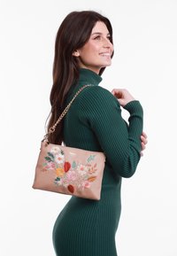 Helle beige Ledertasche mit buntem floralem Stickmuster, Kettenriemen, rechteckiger Form, glatter Textur und dezentem Markenlogo oben.