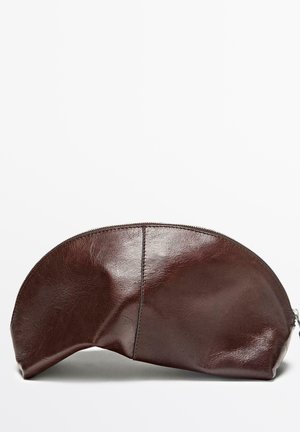 Bruine leren buidel met een afgeronde bovenkant, ritssluiting en een gladde textuur. Heeft een gestikte naad langs de zijkant. Platte basis voor stabiliteit.