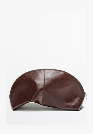 Brun læderpose med rundet top, lynlås og glat tekstur. Har en syning langs siden. Flad bund for stabilitet.