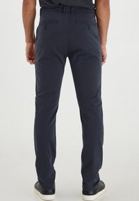 Temno modri ležerni hlače s slim fit krojem, z zadnjimi žepi in gladko teksturo. Narejene so iz lahkega bombažnega mešanega materiala.