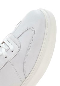 Baskets en cuir blanc avec un bout arrondi, semelle en caoutchouc blanc texturé et coutures ton sur ton. Caractéristiques : lacets plats blancs et design minimaliste.