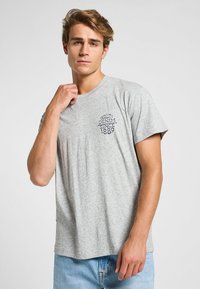 Camiseta de algodón gris con mangas cortas, cuello redondo y logotipo bordado "Quality Denim Since 1889" en el lado izquierdo del pecho.