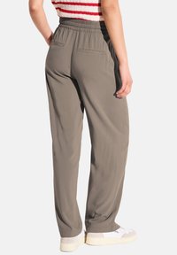 Lichte, olijfgroene, loszittende broek met een elastische tailleband, voorzien van twee achterzakken en een gladde textuur.