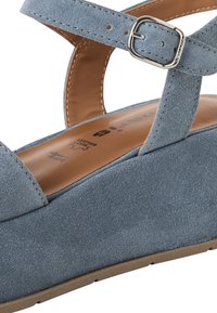 Modra semišova wedge sandal z vložkom za zaponko, gladkim usnjeni notranjosti in teksturiranim zunanjim delom. Ima zaokrožen prst in ravno gumijasto podplat.