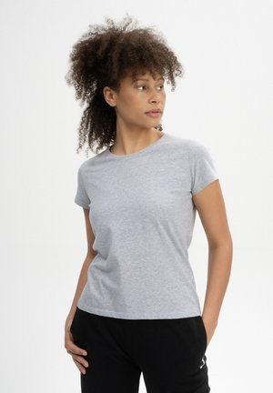Grijze T-shirt met korte mouwen van zachte katoen, voorzien van een ronde halslijn en een relaxte pasvorm. Gecombineerd met zwarte broeken.