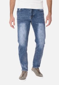 Jeans in denim di un blu chiaro con effetto sbiadito, design a cinque tasche e vestibilità dritta. Abbinati a sneakers grigie.