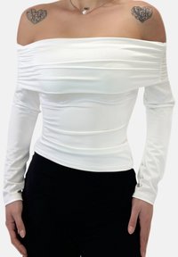 Hvid off-shoulder top lavet af glat, elastisk materiale med lange ærmer og detaljer med rynket stof langs kroppen.