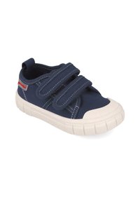 Zapatilla de lona navy con dos tiras de velcro, suela de goma blanca, puntera reforzada y costuras en contraste. Durable y diseñada para la comodidad.