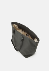 Borsa tote in pelle grigia con superficie texturizzata, doppi manici e un interno chiaro che presenta una tasca con zip e un'etichetta del marchio.