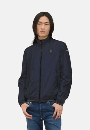 Giacca leggera navy con chiusura a zip, colletto alla francese, due tasche laterali, tessuto testurizzato e dettaglio del logo sulla manica.