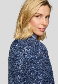 Blauer strukturierter Pullover mit einer flauschigen, schäbigen Oberfläche; zeichnet sich durch eine lockere Passform und leicht geschwungene Schultern aus. Akzentuiert durch einen subtilen Glanz.
