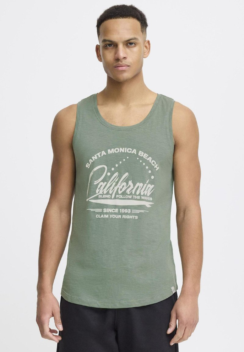 Zeleni top s okruglim izrezom i ležernim krojem, s bijelim grafičkim natpisom "Santa Monica Beach California."