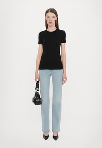 Black fitted t-shirt, short sleeves, paired with light blue straight-leg jeans. Black handbag with hardware details and pointed black heels.