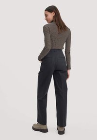 Zwarte wijde broeken gecombineerd met een zwart en gestreept T-shirt met lange mouwen. Heeft achterzakken en een stijlvolle, gladde textuur.