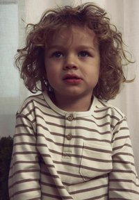 Beżowa, w paski bawełniana koszula z długim rękawem w brązowe paski, z zapięciem na guziki i kieszenią na piersi. Miękka w dotyku.