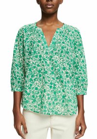 Blusa floreale verde e crema con scollo a V, maniche a tre quarti, tessuto leggero e vestibilità ampia. Presenta una sottile consistenza in tutto il capo.
