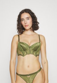 Grøn blonde og satin bh med bøjle og dekorativ sløjfe i midten, parret med matchende gennemsigtige grønne blonde trusser. Begge har justerbare stropper.