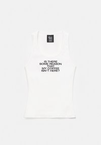 Débardeur blanc sans manches avec texte noir disant : « Y a-t-il une raison que mon café ne soit pas là ? » et une étiquette « The Devil Wears Prada ».