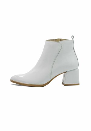 Valkoiset nahka nilkkurit, joissa on paksu korko, kärjessä terävä muoto, sivusaumadetaileja ja pieni vetotappi takana.