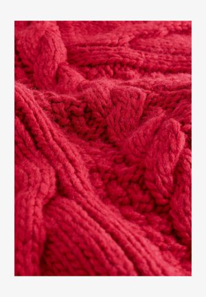 Piros kötött anyag, textúrált kábelmintával. A vastag fonál puha és bolyhos, mély színeket és meleg, otthonos megjelenést kölcsönöz.