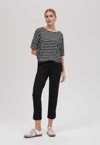 Black and white striped short-sleeve top, black pants, and light-colored sneakers with a textured sole. Simple design with relaxed fit.
