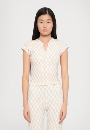 Fitted, short-sleeve top in white with a subtle, repeated tan geometric pattern and a v-neckline, paired with matching bottoms.