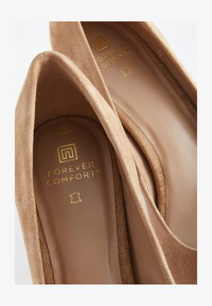 Beige Wildleder-Absätze mit abgerundeter Spitze und glattem Innenfutter. Goldene Prägung "FOREVER COMFORT" auf der Innensohle.