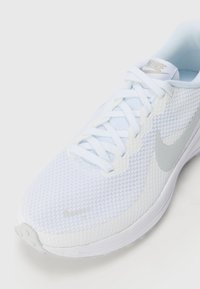 White athletic shoe with a textured mesh upper and silver swoosh. Features flat laces and a padded tongue, designed for comfort and breathability.