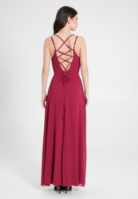 Burgunderfarbenes Maxikleid mit einem Schnürung auf dem Rücken, dünnen Trägern und einer schwingenden Silhouette. Der Stoff hat eine glatte, leichte Textur.