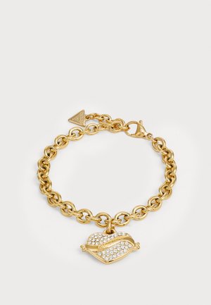 Gold chain bracelet with a heart-shaped charm adorned with clear crystals. Features a lobster clasp and a triangular brand tag.