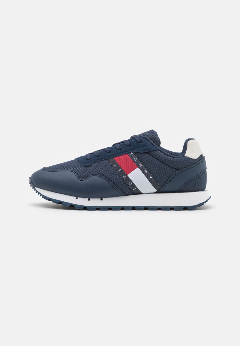 Sneaker blu navy con un верх in tessuto texture, caratterizzate da una suola intermedia bianca e strisce rosse e bianche sui lati.