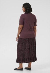 Short-sleeve purple top paired with a long, dark floral skirt featuring a ruffled hem, complemented by black flats.