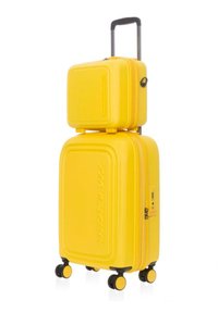 Set di valigie gialle con guscio rigido e finitura testurizzata, composto da una valigia grande e da una più piccola impilata sopra. Presenta quattro ruote.